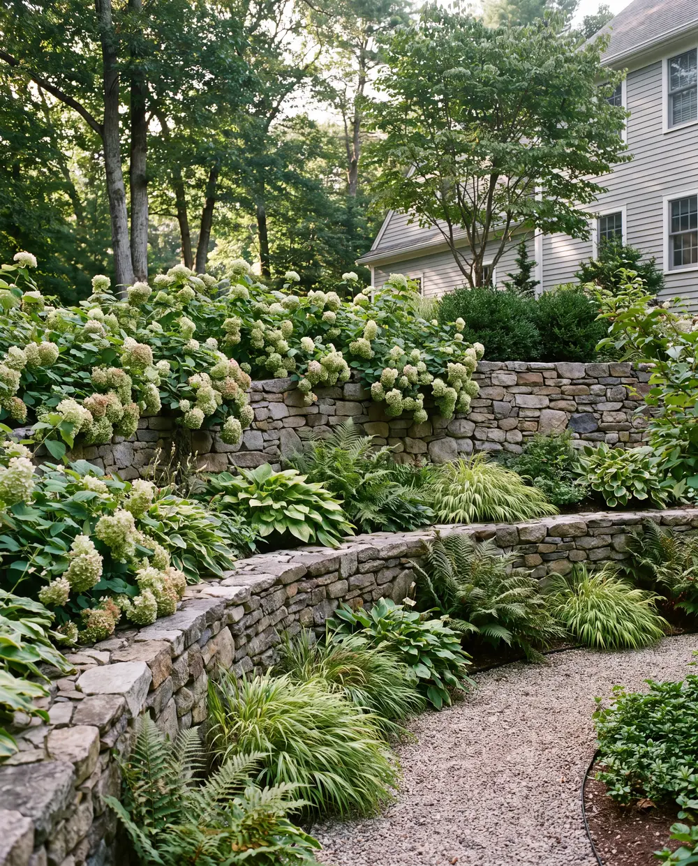 Curved natural stone retaining wall with plantings on top in a residential garden